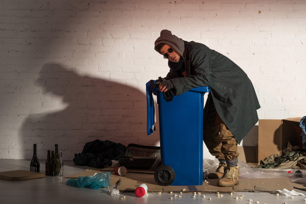 senzatetto in abiti scuri rovistando nel contenitore della spazzatura
  - Foto, immagini