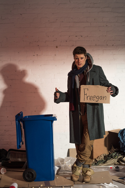 senzatetto che mostra ok segno e in possesso di carta di cartone con iscrizione "freegan"
 - Foto, immagini