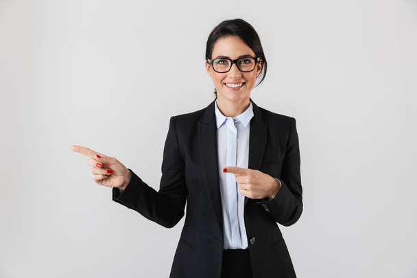 Portrait of european businesswoman 30s in formal wear and eyeglasses pointing fingers aside isolated over white background - Фото, изображение