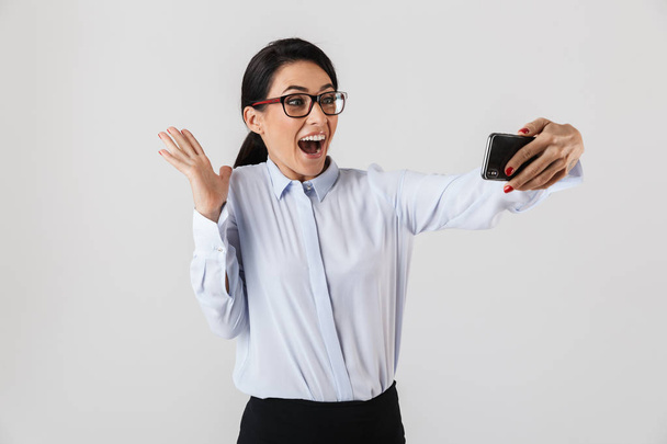 Happy excited businesswoman smartly dressed standing isolated over white background, taking a selfie - Fotoğraf, Görsel
