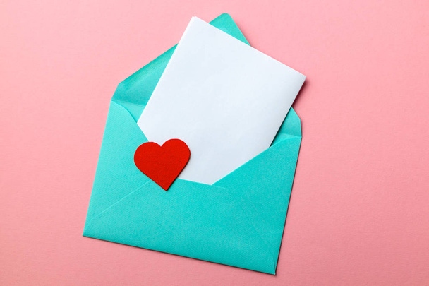 Love letter. Message of declaration of love. Green envelope with hearts and blank letter on pink background - Fotoğraf, Görsel