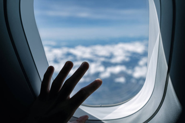 Vue de la fenêtre de l'avion. Paysage aérien. Survoler les nuages. Toucher le verre à la main
 - Photo, image