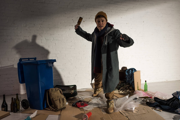 Betrunkener Obdachloser steht mit leerer Flasche in Angriffspose - Foto, Bild