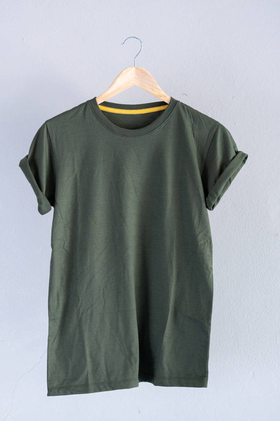 Retro fold green cotton T-Shirt clothes mock up template on gray cement background concept for retail dress shop backdrop, Blank flat lay vintage grey wall plain laundry advertising - Photo, Image
