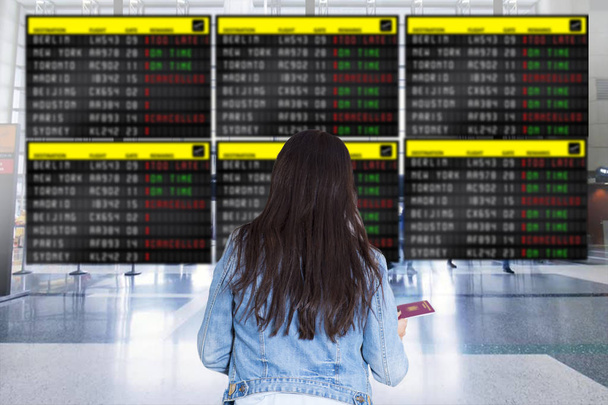 Nainen matkustaja katsomassa lentokentällä mainostaulu hänen viivästynyt lento
 - Valokuva, kuva