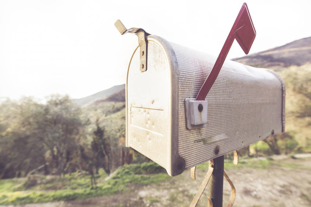 Caixa de correio de metal com estilo típico americano, atrás de você vê uma paisagem rural
 - Foto, Imagem