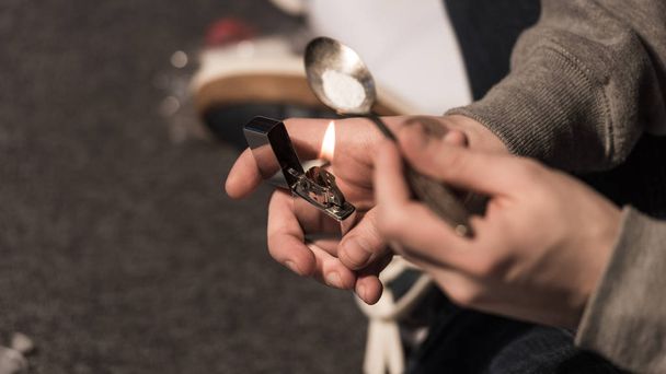 selective focus of junkie man boiling heroin in spoon on lighter - Photo, Image