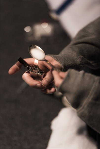 Selektywny fokus junkie człowieka wrzenia heroiny w łyżką na lżejsze - Zdjęcie, obraz