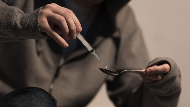 foco seletivo do viciado homem que enche a seringa com heroína
 - Foto, Imagem