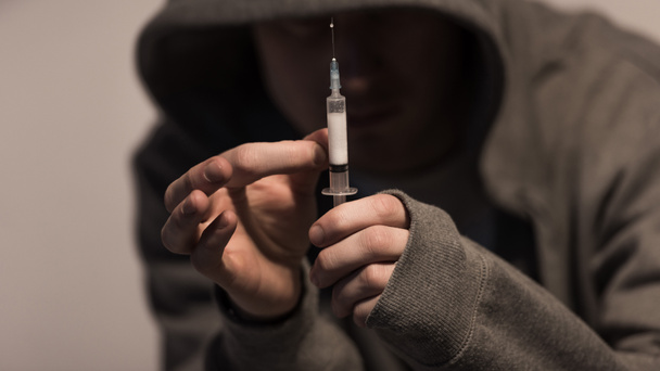enfoque selectivo del hombre drogadicto sosteniendo la jeringa con dosis de heroína
 - Foto, Imagen
