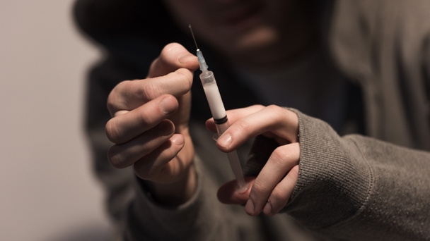 selectieve aandacht van verslaafde man spuit met dosis heroïne te houden - Foto, afbeelding