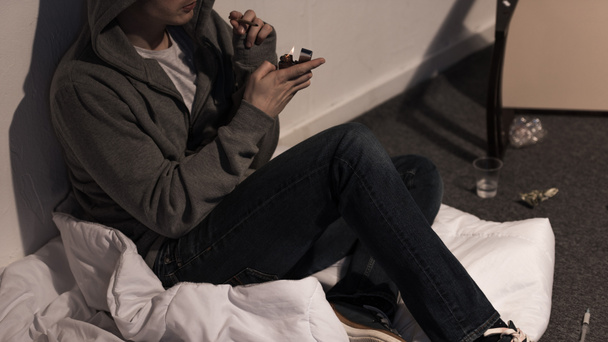 junkie man holding marijuana rolled cigarette and lighter - Photo, Image