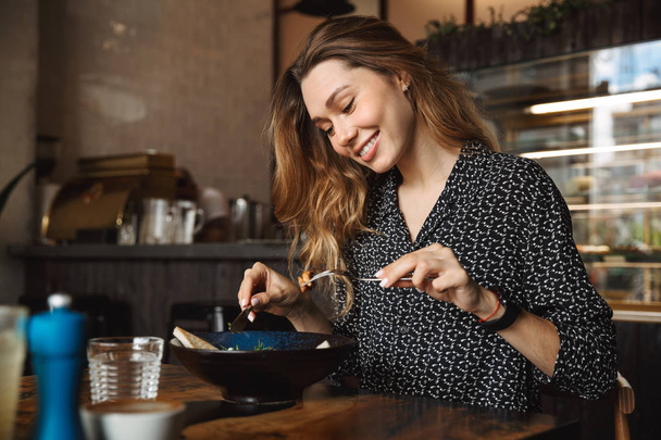 Photo of excited beautiful young pretty woman sitting in cafe indoors have a breakfast. - Фото, зображення