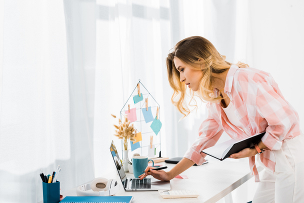 Mujer joven concentrada con portátil usando el ordenador portátil en la oficina en casa
 - Foto, Imagen