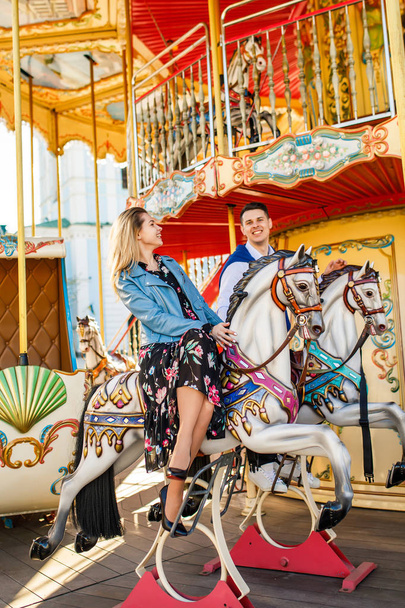 happy couple sitting on carousel horses - Fotó, kép
