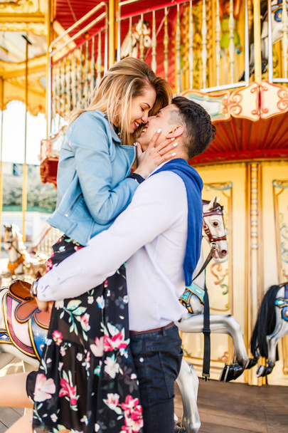 happy couple, young man holding his girlfriend at carousel - Foto, imagen