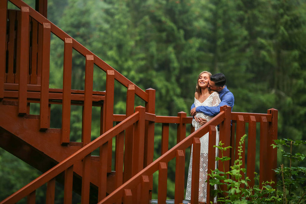 Beautiful wedding couple posing in nature at wooden structure - Zdjęcie, obraz
