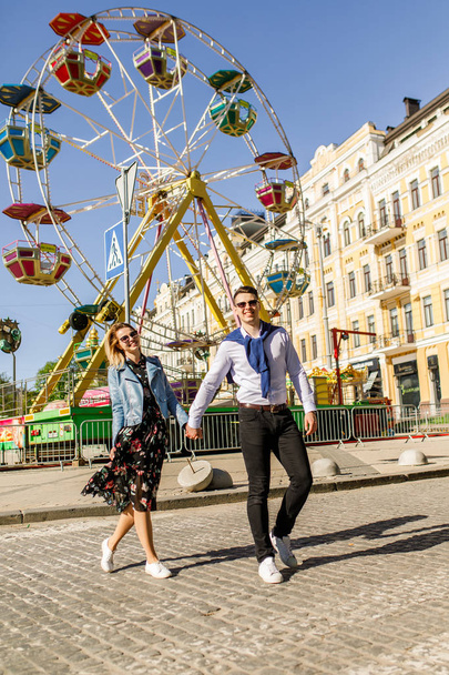 smiling couple holding hands by ferris wheel on street - Photo, Image