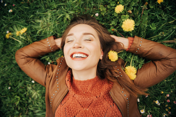 Close up portrait of young beautiful woman with brown hair lying on grass - Photo, Image