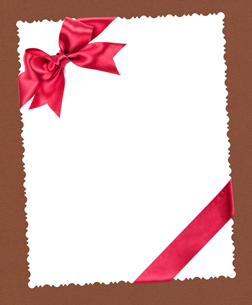 hoja de papel en blanco con lazo rojo sobre marrón
 - Foto, Imagen