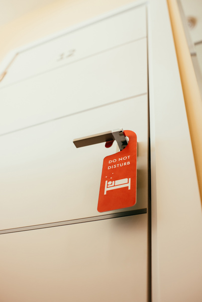 red symbol with "do not disturb" lettering on door handle in hotel - Zdjęcie, obraz