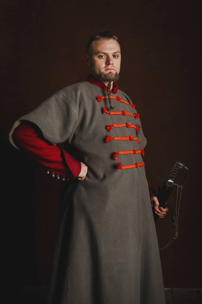 Muotokuva miehestä keskiaikaisessa puvussa tummalla taustalla. Puolalaisen herrasväen vaatteet. Ylpeä, tiukka mies aloittaa historiallisessa asussa
 - Valokuva, kuva