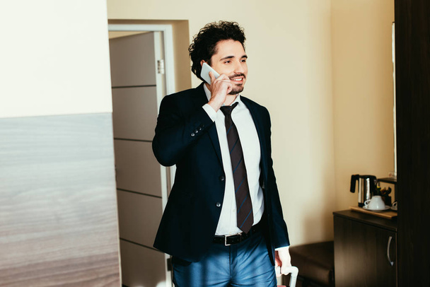 Geschäftsmann spricht auf Geschäftsreise im Hotelzimmer mit Smartphone - Foto, Bild