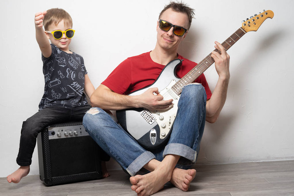 Happy father and little son playing guitar together - Fotografie, Obrázek
