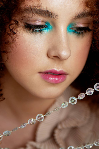 A girl with lush curly red hair. Closely photographed doll false eyelashes.Doll makeup. - Fotografie, Obrázek