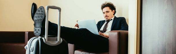 rete di uomini d'affari su laptop con gambe sulla valigia in camera d'albergo
 - Foto, immagini