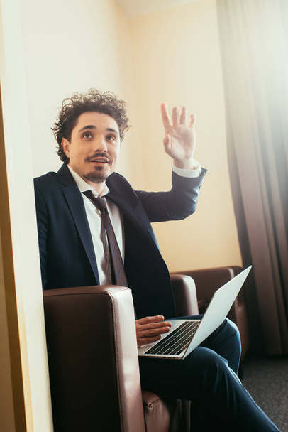 бизнесмен жестом во время работы на ноутбуке в гостиничном номере
 - Фото, изображение