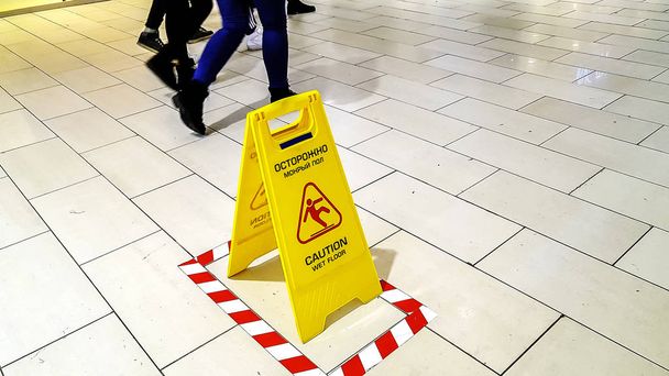 Pointer on the floor with a warning "wet floor". Bright yellow. - Photo, Image