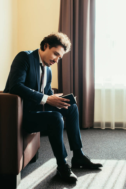 businessman holding passport and sitting in hotel room - Foto, Bild