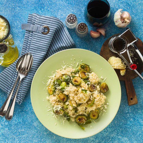 Italian spring risotto with Brussels sprouts and parmesan cheese on the table. healthy food for the whole family, party or restaurant menu and red wine - Fotografie, Obrázek