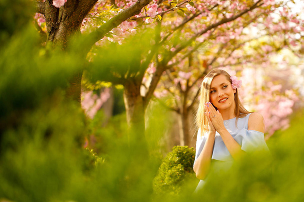 Outdoor fashion photo of young beautiful lady surrounded spring leaves - Fotografie, Obrázek