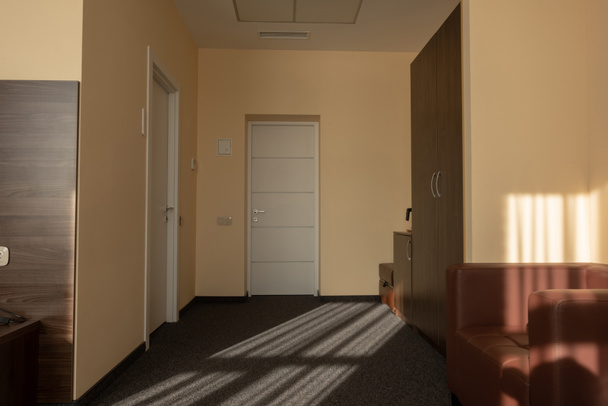 interieur van de kamer van de beige hotel met garderobe, fauteuil en deuren  - Foto, afbeelding