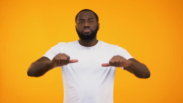 selbstbewusster afrikanisch-amerikanischer Mann gibt harte Daumen nach unten auf gelbem Hintergrund - Filmmaterial, Video