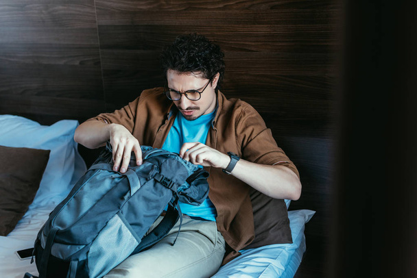 male tourist looking into backpack in hotel room  - Φωτογραφία, εικόνα