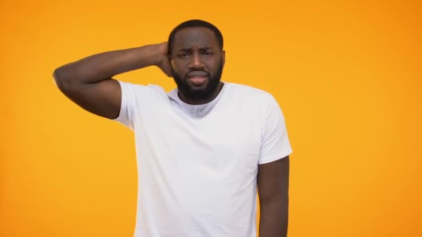 Young african american man shrugging in confusion, isolated on yellow background - Imágenes, Vídeo
