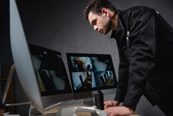 зосереджений охоронець у формі, дивлячись на монітор комп'ютера на робочому місці
  - Фото, зображення