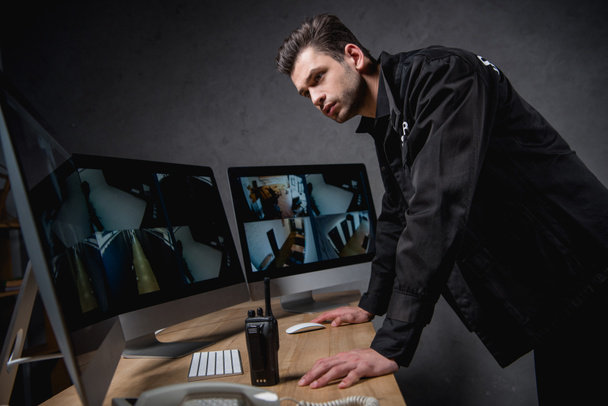 guardia focalizzata in uniforme guardando il monitor del computer nello spazio di lavoro
 - Foto, immagini