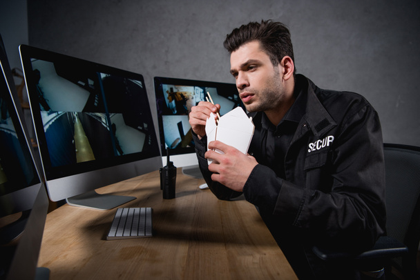 guard eating junk food and looking at computer monitor  - Photo, Image