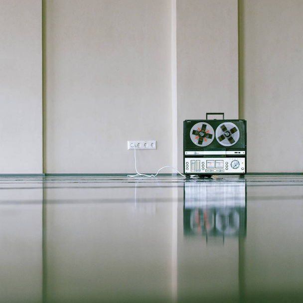 vintage grabadora de cinta magnética analógica de pie en el suelo cerca de la pared
 - Foto, Imagen