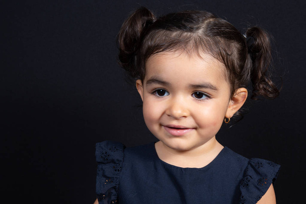 cute looking down portrait child girl in black background - Photo, Image