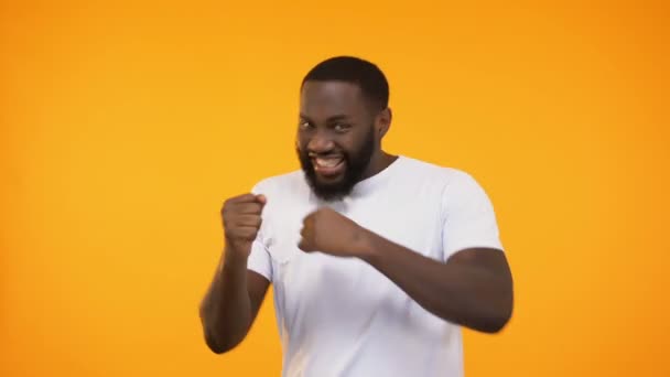 Young black guy celebrating success by dancing, isolated on yellow background - Footage, Video