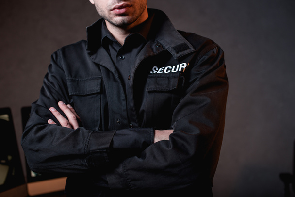 cropped view of guard in uniform with crossed arms at workplace - Фото, зображення
