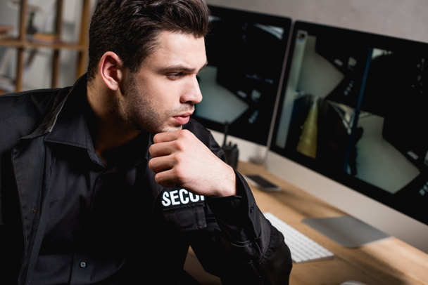 thoughtful guard in uniform looking at computer monitor at workplace  - Foto, Imagem