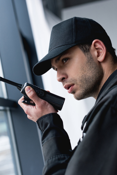 close up of guard in black uniform using walkie-talkie  - Zdjęcie, obraz