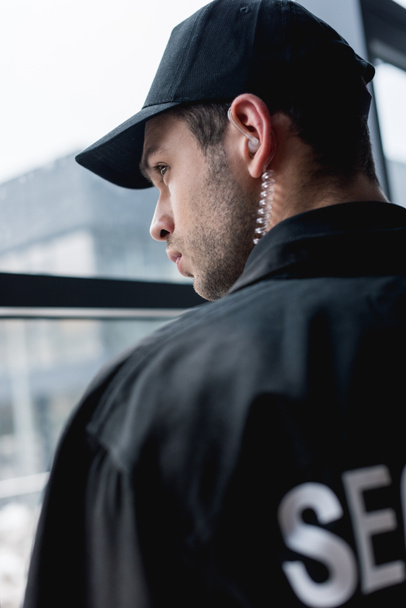 handsome guard in black uniform with earphone looking away  - Fotó, kép