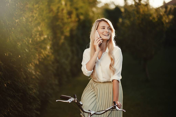 portrait of pretty sexy girl  posing with vintage  retro bicycle using smartphone. - Fotografie, Obrázek